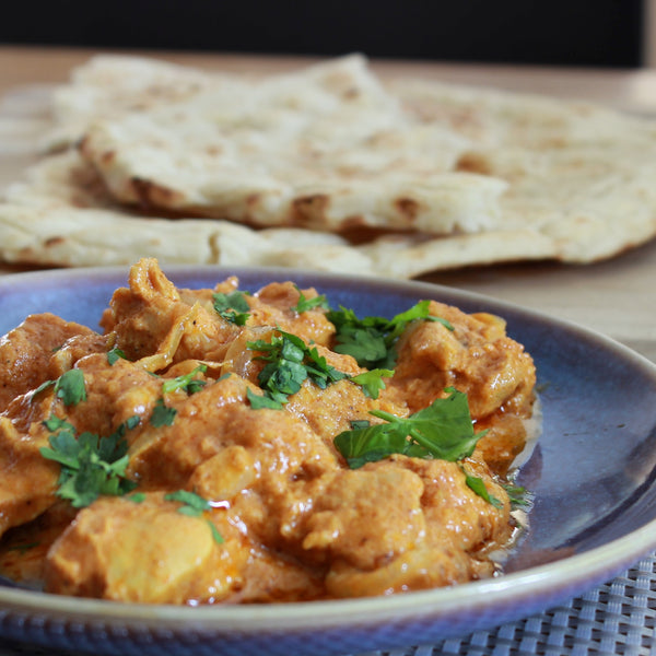 A plate of Butter Chicken made with a Case for Cooking spice kit and served with naan bread