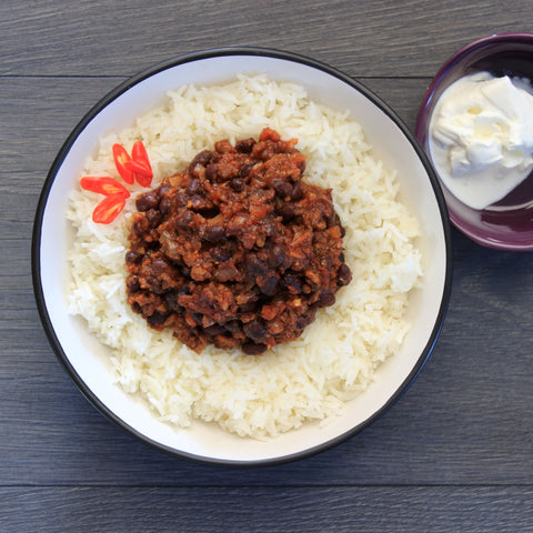 Veg & black bean chilli meal with rice on a plate.